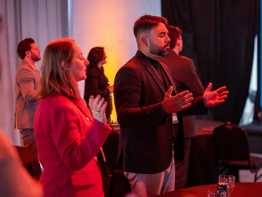 Participantes conversando em pé no lounge do evento